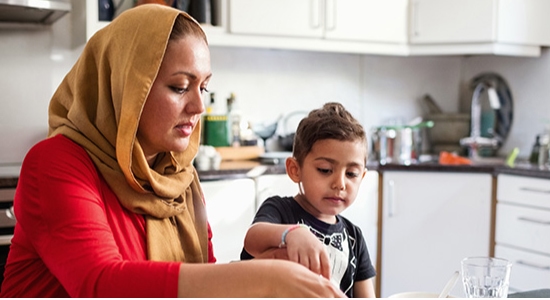 A mum and her young son prepare food in a home kitchen