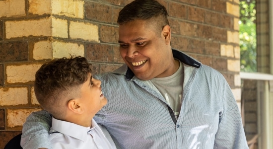 A man puts his arm around a student’s shoulder as they smile at each other