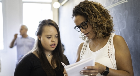A teacher discussing notes with a student in a classroom setting