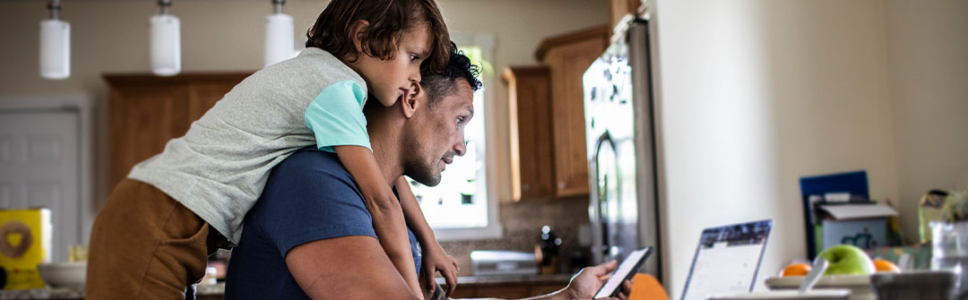 father and son looking at laptop together at home