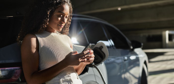 Female researching on her mobile device while her electric vehicle is charging