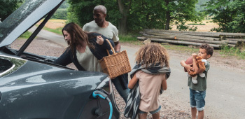 Family unpacking picnic items from the boot of their electric vehicle