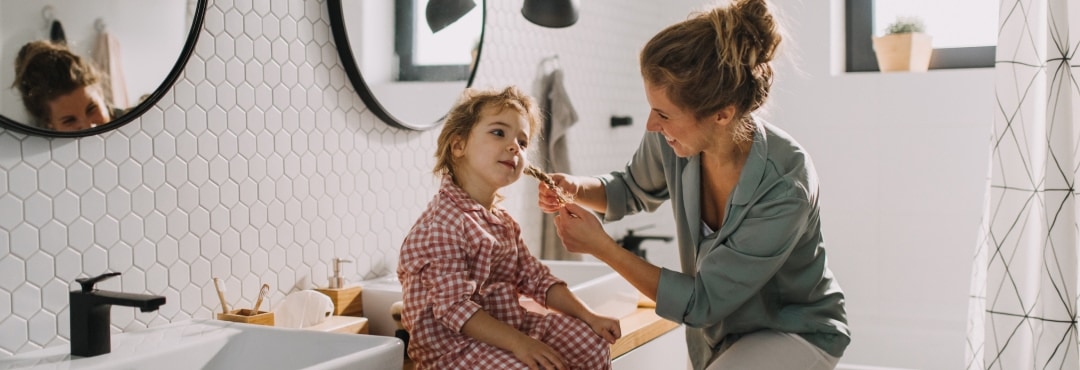 A lady tieing her kid hair in the bathroom