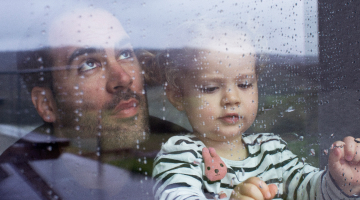 Dad and daughter looking out of a rainy window