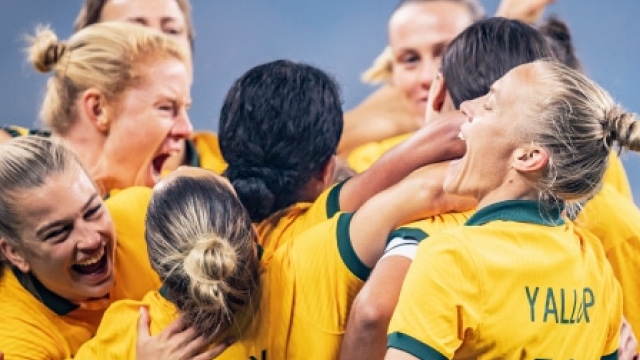 business people walking up stairs The Matildas in a celebratory group hug