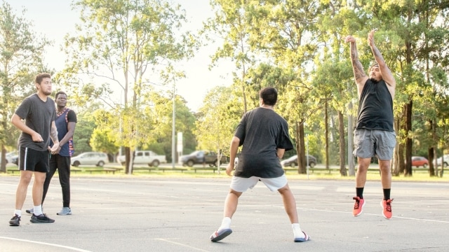 Guys playing basketball outdoors