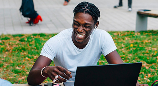 Man smiling as he looks at a laptop