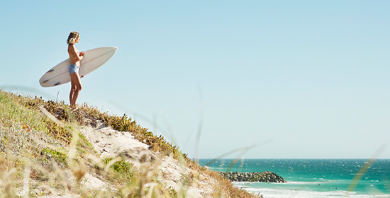 Woman with surfboard looking at the ocean