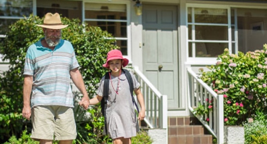 A dad holding his school-aged daughter’s hand